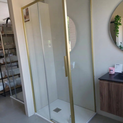 Foto reale del box doccia scorrevole profili oro installato in bagno con specchio tondo e mobile in legno