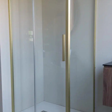 Foto reale del box doccia scorrevole profili oro con lato fisso installato su piatto doccia bianco filo pavimento