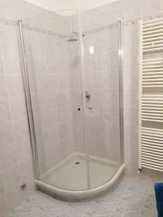 Box doccia semicircolare Cassiopea cristallo 6mm H190 installato in bagno reale con termoarredo e piastrelle chiare