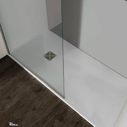 Piatto doccia in marmo resina bianco ribassato posato a filo su parquet scuro, con parete doccia in cristallo e piletta in tinta
