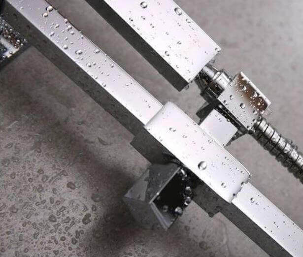 Dettaglio macro profilo cromato squadrato con gocce d'acqua, finitura lucida