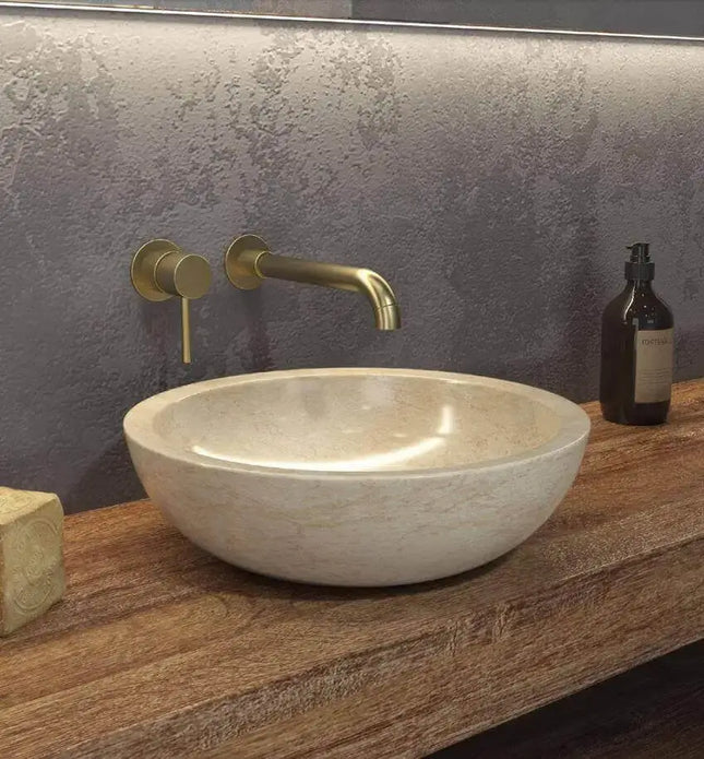 Lavabo basso marmo crema Karag Elena 40cm su piano legno: profilo ovale piatto con interno lucidato beige caldo e rubinetteria oro a muro