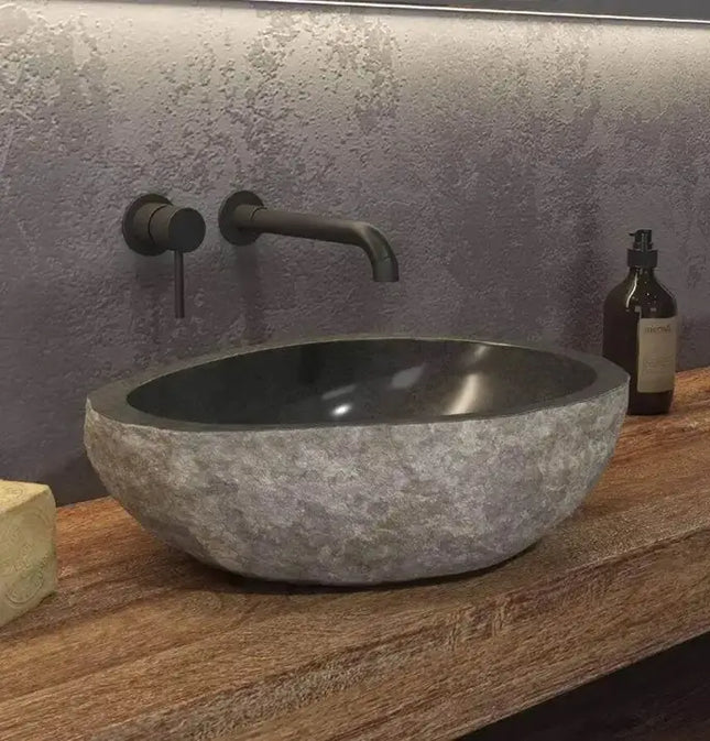 Lavabo da appoggio in pietra di fiume naturale grigio Karag River 40-45cm: esterno grezzo, interno scuro lucidato, su piano legno con rubinetteria nera