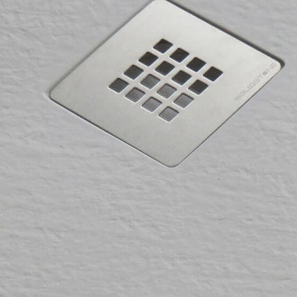 Dettaglio griglia di scarico cromata quadrata SolidStone su piatto doccia semicircolare bianco mineral marmo