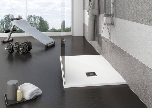Piatto doccia bianco mineral marmo ambientato in bagno moderno con cabina vetro, doccia a soffione e zona fitness