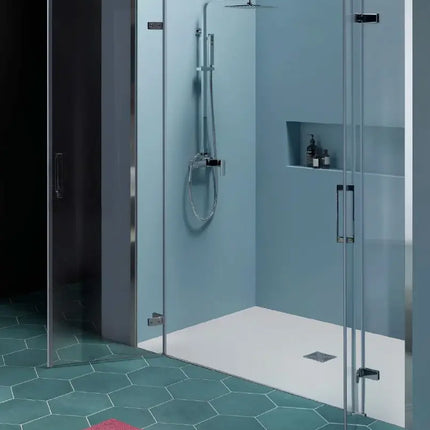 Porta doccia doppia battente 8mm Infinity con ante aperte a 90°, vista laterale in bagno con pavimento esagonale verde-turchese